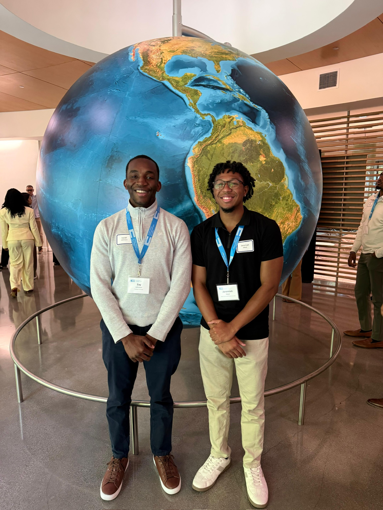 Two students standing in front of a large globe